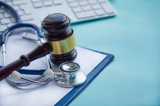 A judge's hammer on top of a doctor's stethoscope and folder.