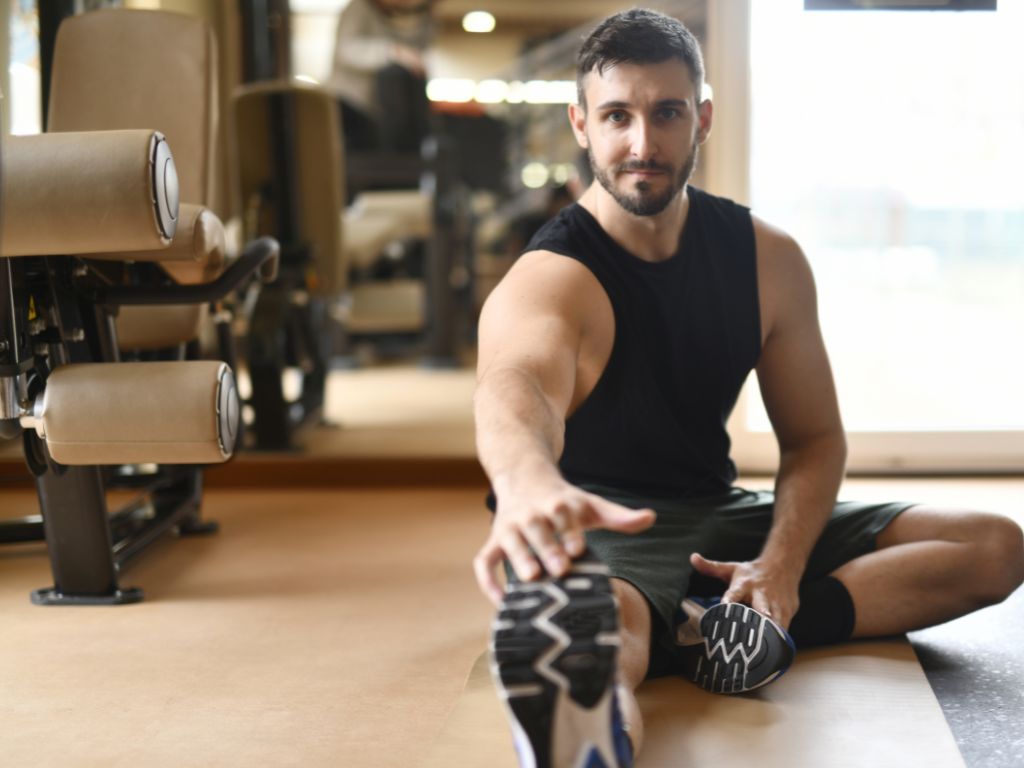 A man stretching his hand out to his foot