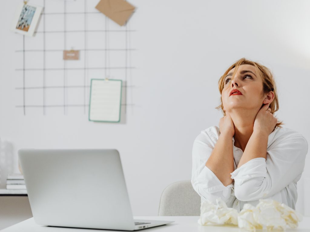 A woman looking up at the sky while her laptop is out on her desk