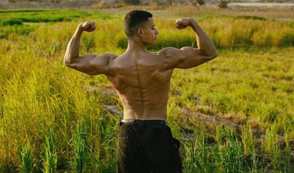 A man flexing while facing an open field