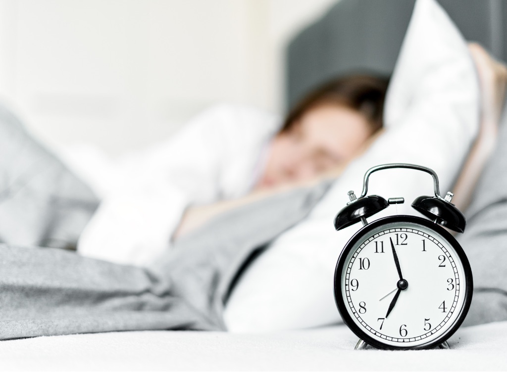 Woman sleeping with an alarm clock on her bed